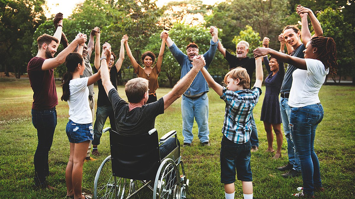 Diverse group of people including wheelchair user holding hands together in park representing social connectedness and community in Social Sciences diploma at Sipway International Campus